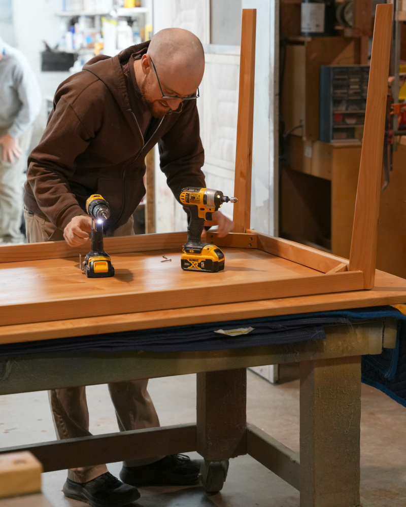 Craftsperson attaching the dining table base during final assembly