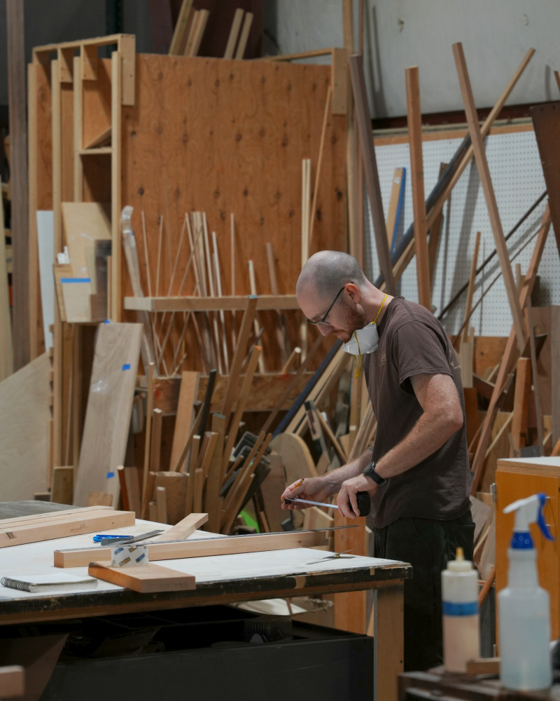 Woodworker measuring and marking lumber for the custom dining table