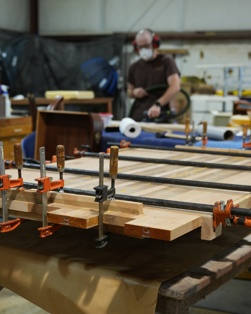 Solid wood tabletop panels in clamps during glue-up at G. Michael's Restoration
