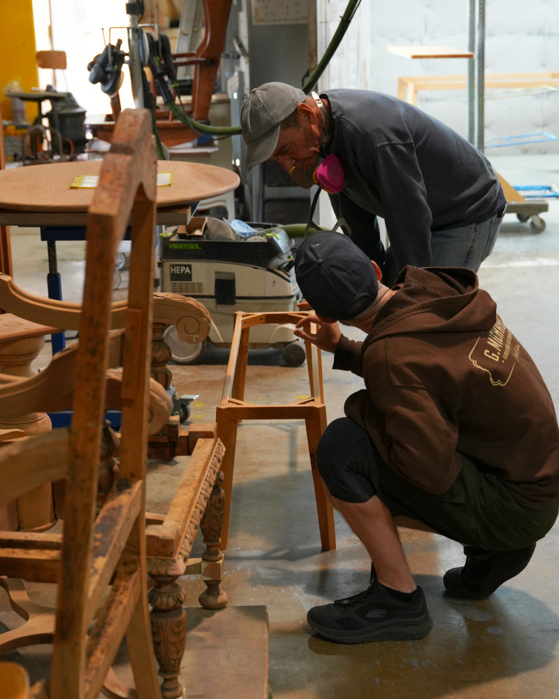 Two craftspeople inspecting the bench frame before finishing