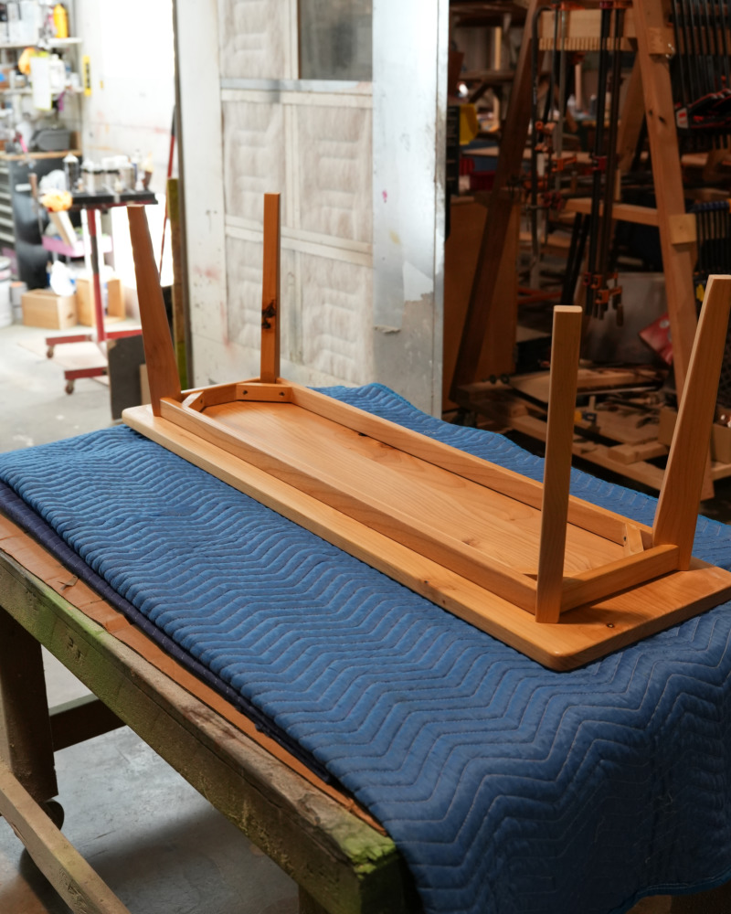 Assembled custom bench upside down, showing its angled legs and apron frame