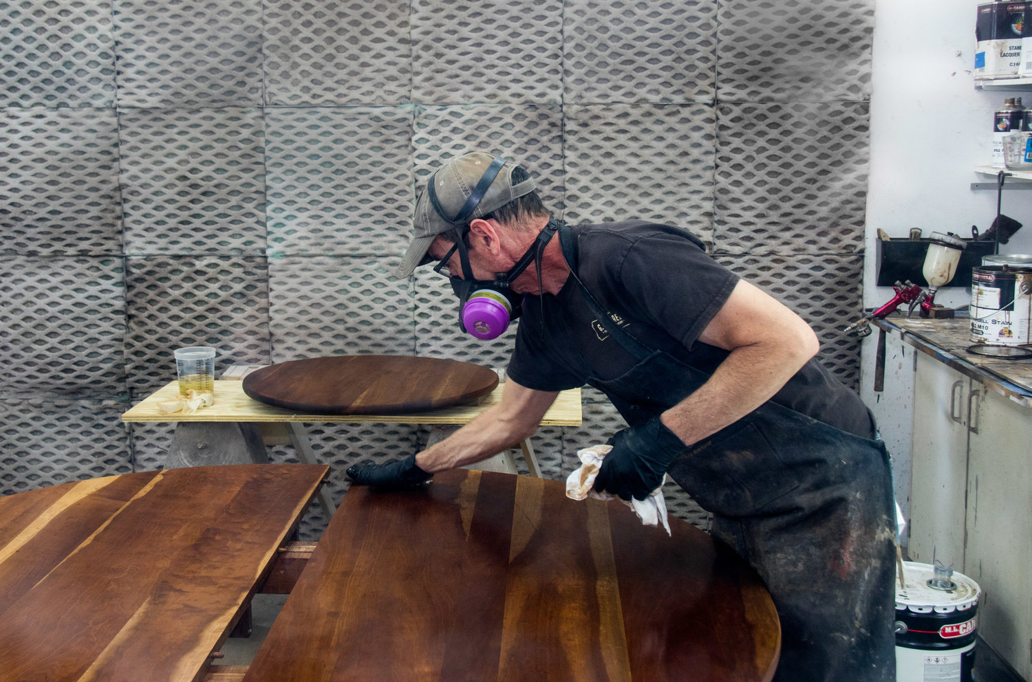 A G. Michael's craftsperson applying finish to a restored wood table